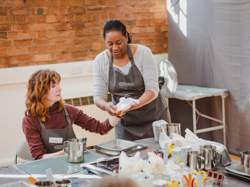 A teacher is helping her student at a candle making class